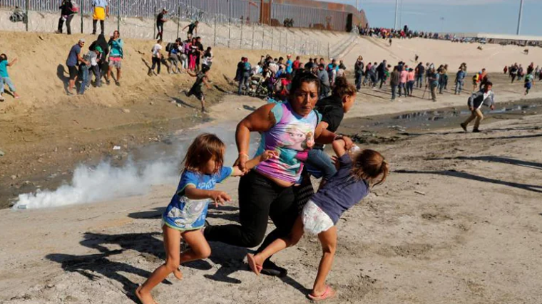 Una familia de migrantes, parte de una caravana de miles de personas que viajan desde Centroamérica rumbo a Estados Unidos, huye de los gases lacrimógenos frente al muro fronterizo entre Estados Unidos y México