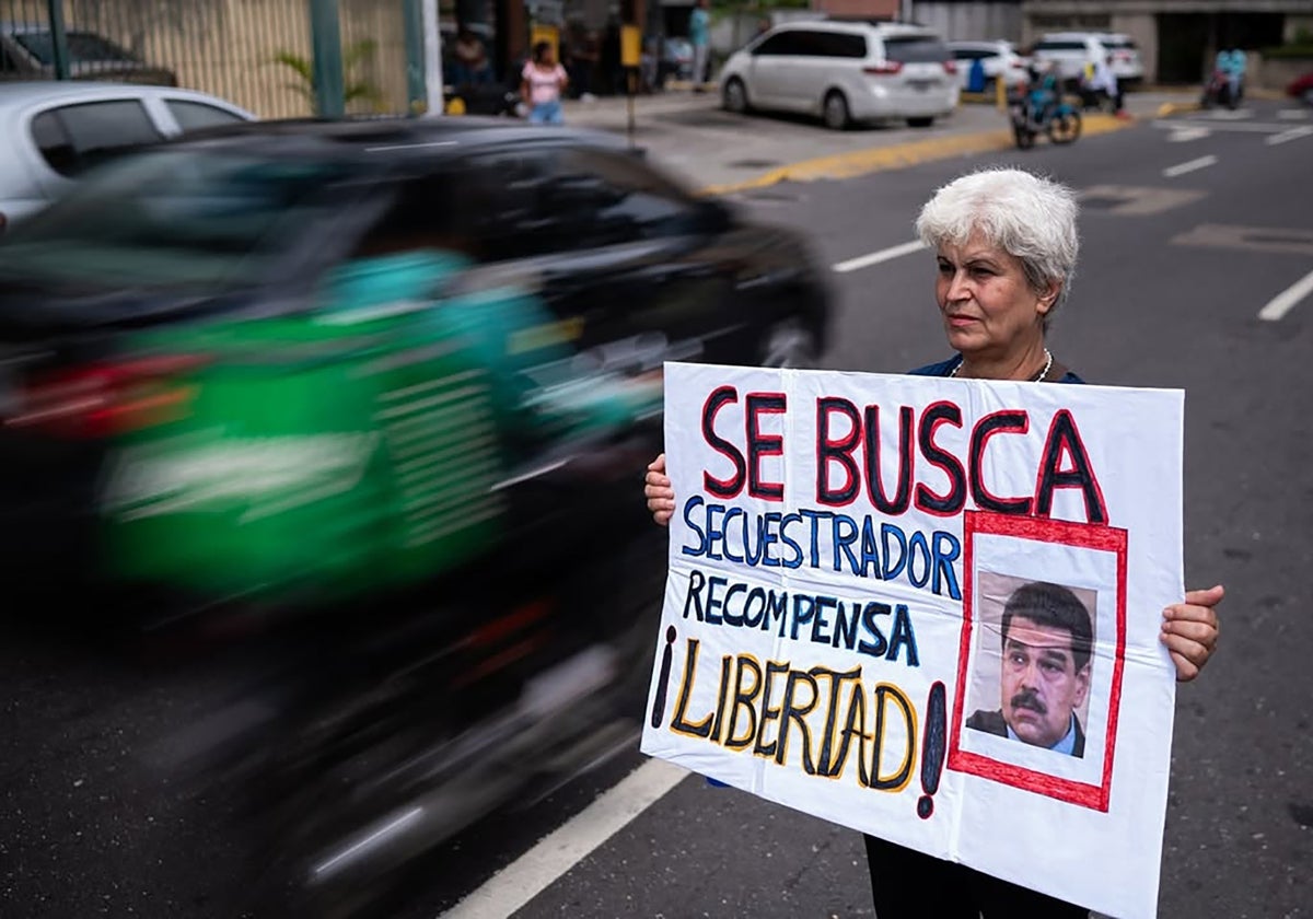 Una manifestante sostiene una pancarta en contra del régimen de Maduro