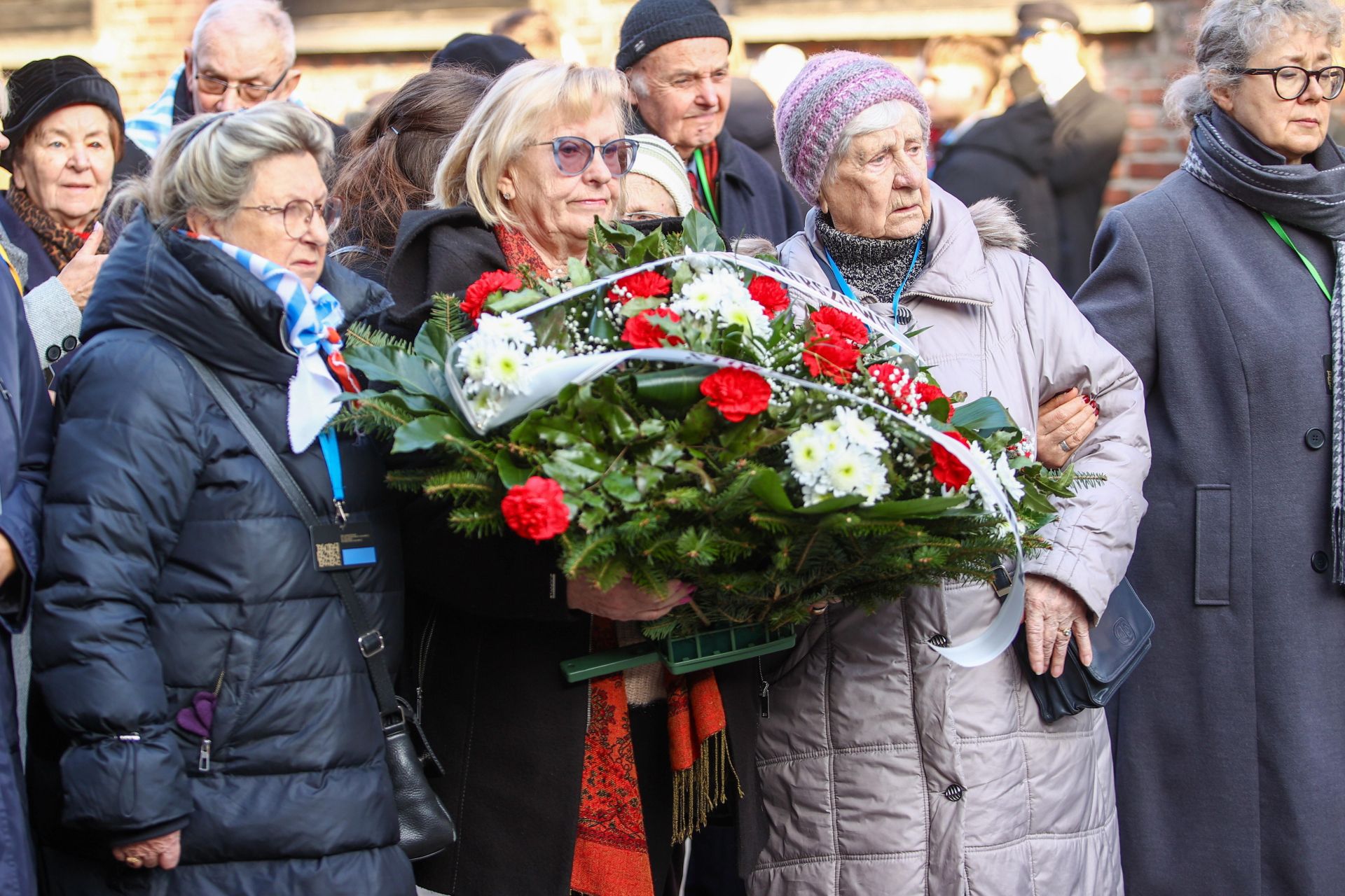 Ex prisioneros asisten a una ceremonia de colocación de coronas de flores frente al Muro de la Muerte