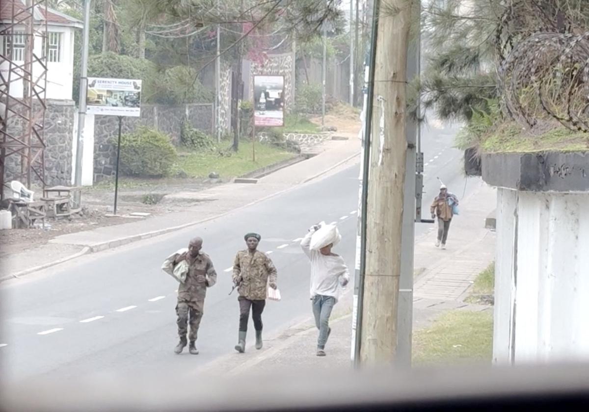 Hombres armados caminando por las calles de la ciudad, algunos de ellos llevando sus pertenencias