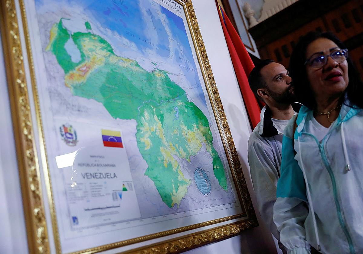 Varias personas de pie durante un evento para presentar un mapa de Venezuela que muestra la disputada región de Esequibo