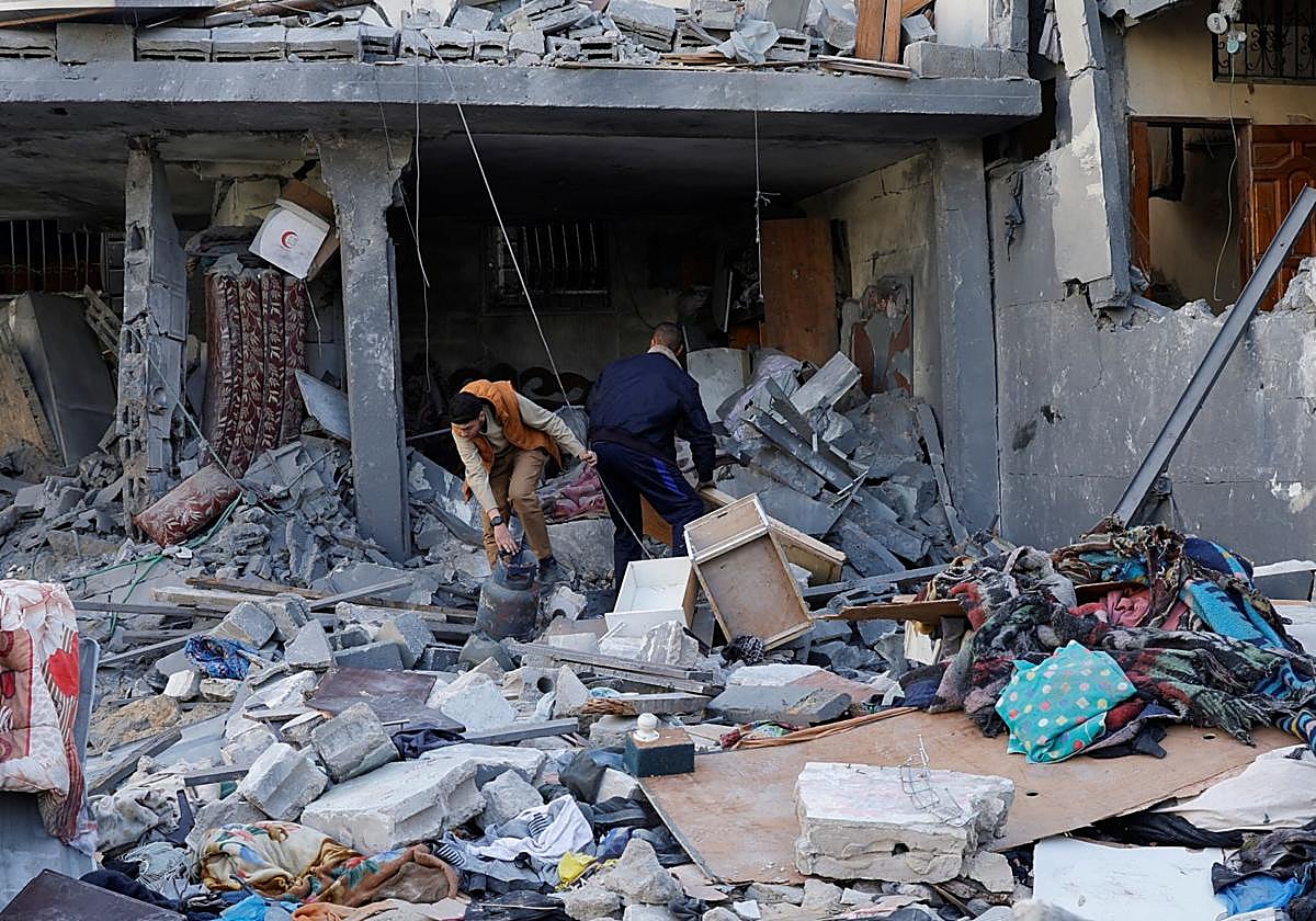 Dos palestinos inspeccionan las ruinas de una casa después de un ataque israelí en Jan Yunís