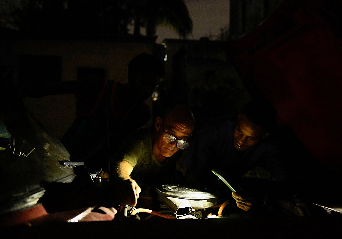El mecánico Juan Raudel intenta arreglar un auto durante un apagón en La Habana