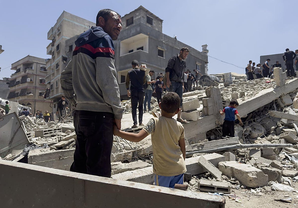Un padre y su hijo, ante los escombros de casas destruidas en Jabalia
