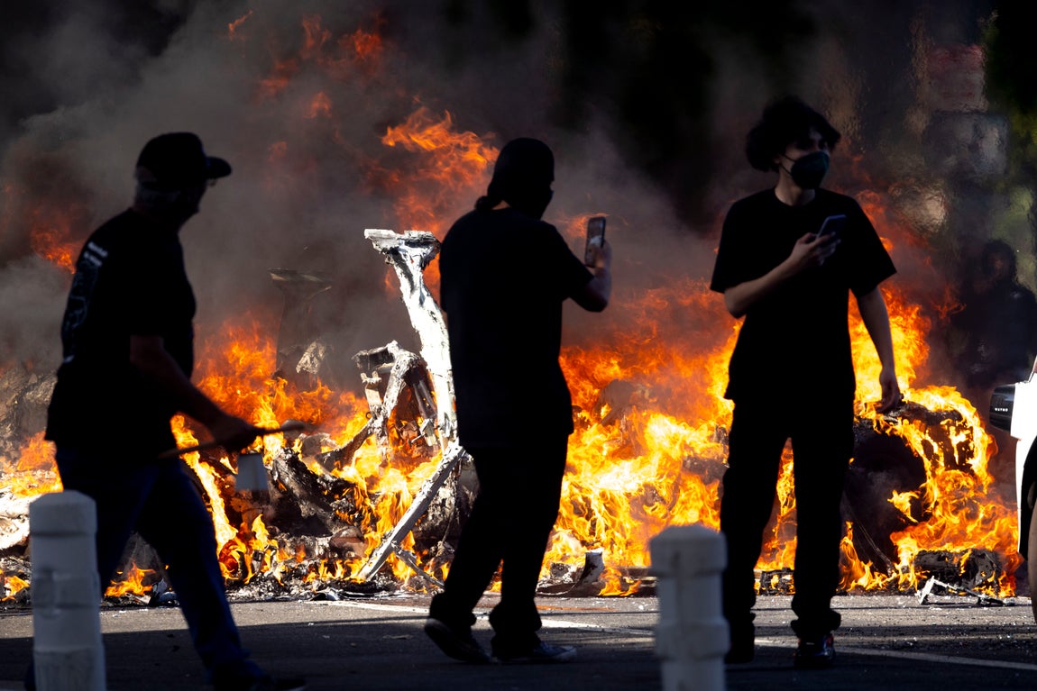 Varias personas observan el fuego durante los disturbios en Los Ángeles.