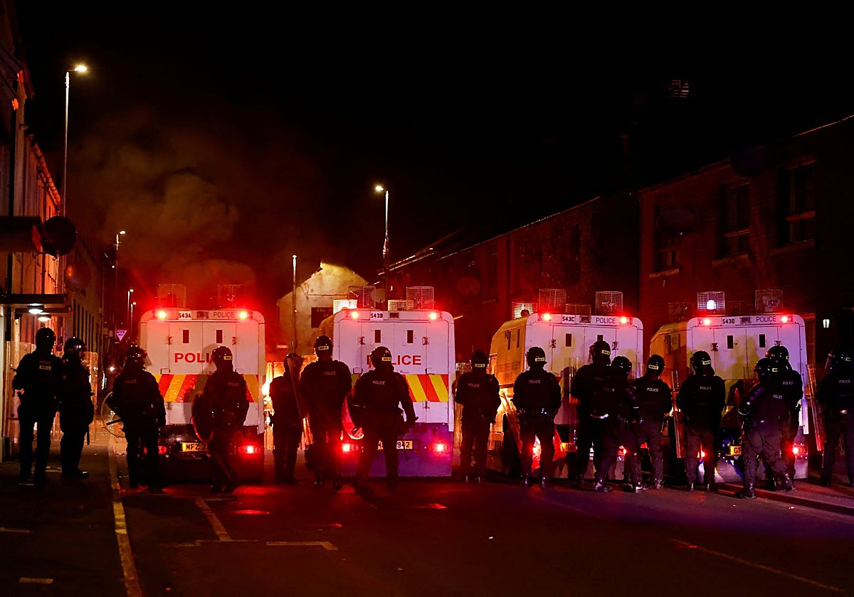 Policías armados con equipo antidisturbios hacen guardia durante una segunda noche de disturbios en Ballymena