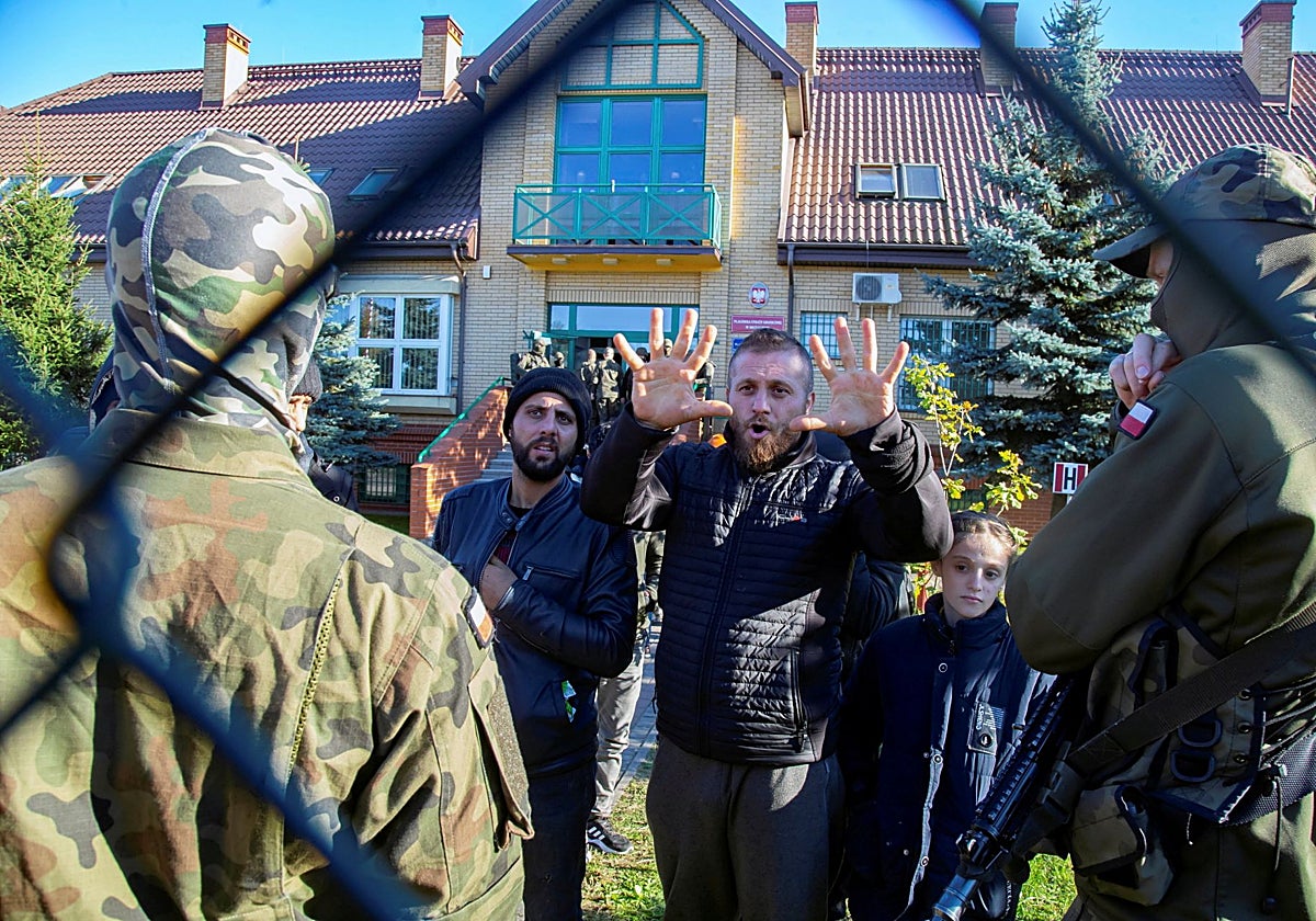 Un grupo de migrantes detenidos tras cruzar la frontera entre Polonia y Bielorrusia se encuentran retenidos frente a la oficina de la guardia fronteriza en Michalowo en 2021
