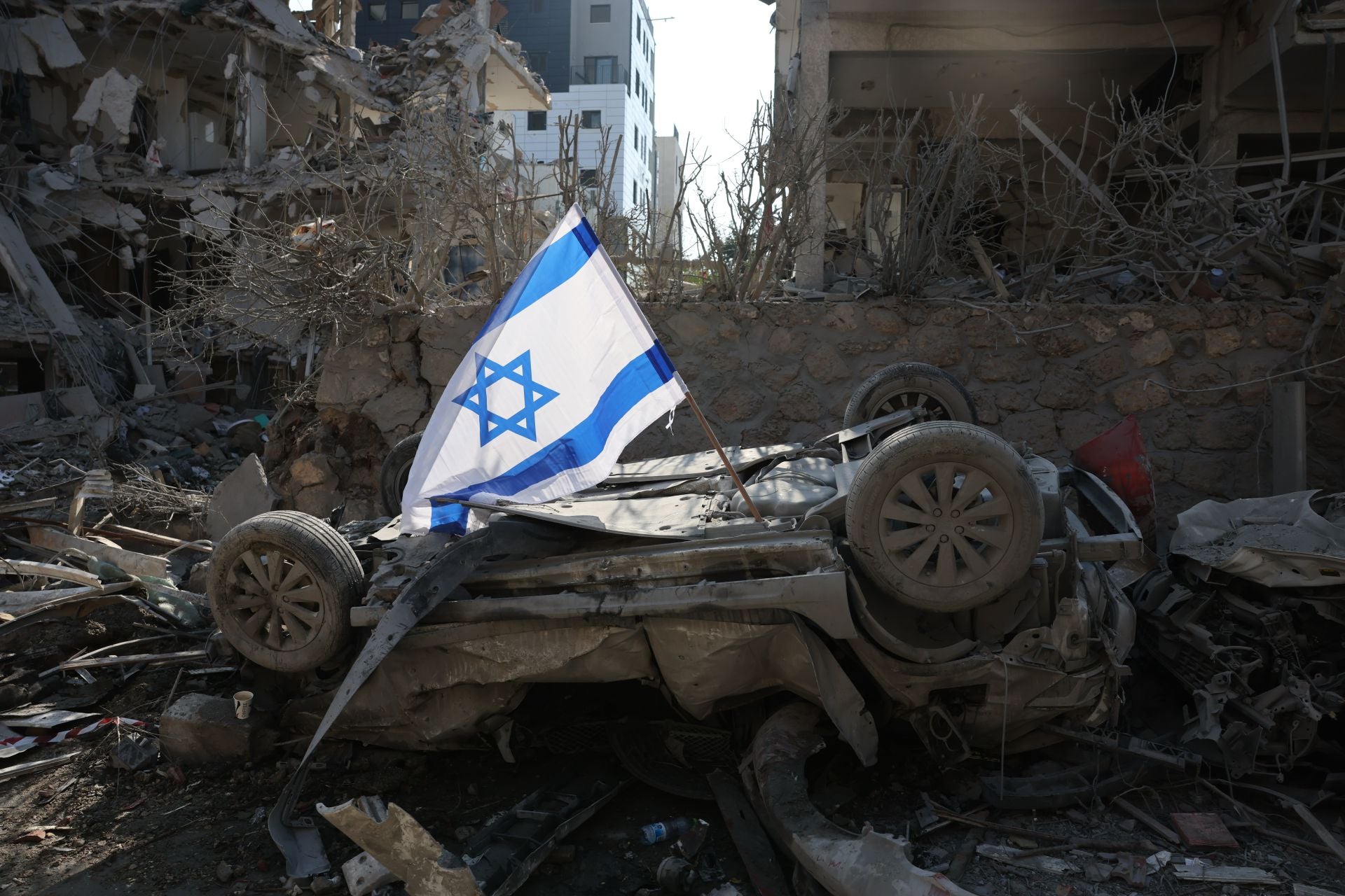 Una bandera israelí colocada sobre un coche dañado tras el impacto de un misil iraní en Tel Aviv