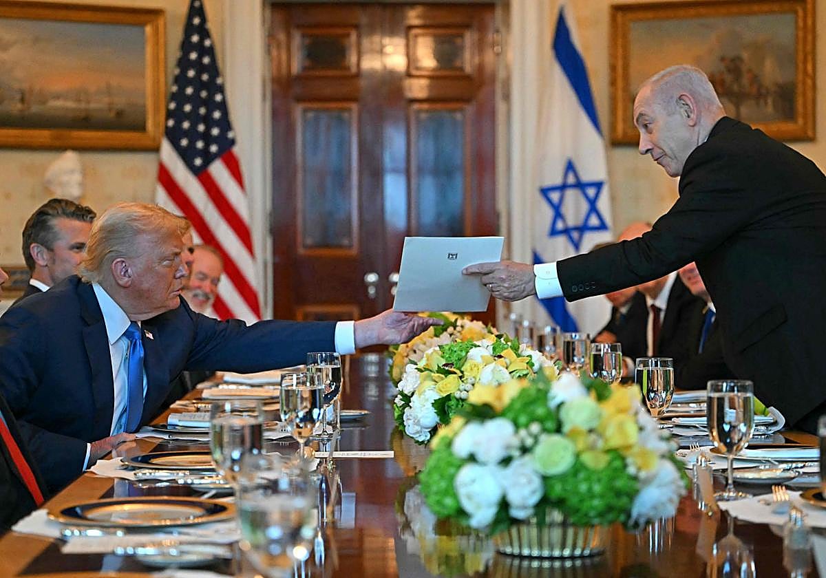 El primer ministro israelí, Benjamin Netanyahu (der.), entrega una carta al presidente estadounidense, Donald Trump, durante su reunión en la Sala Azul de la Casa Blanca en Washington, D.C.
