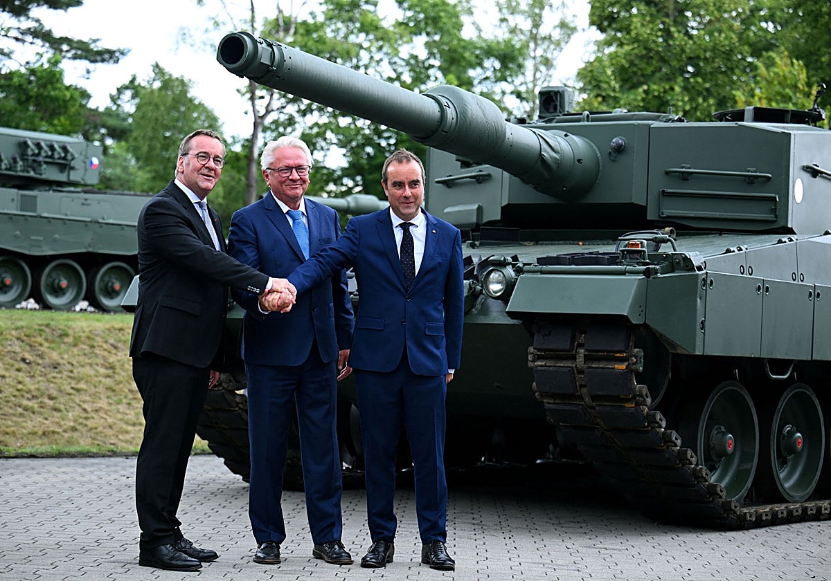 El director general de Rheinmetall (centro), y los ministros de defensa francés (der.) y alemán (izq.) durante una visita a una planta de Rheinmetall