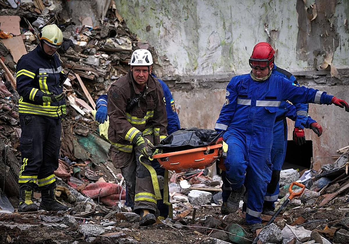 Rescatistas ucranianos cargan el cuerpo de una de las 31 víctimas mortales tras el ataque ruso en Kiev