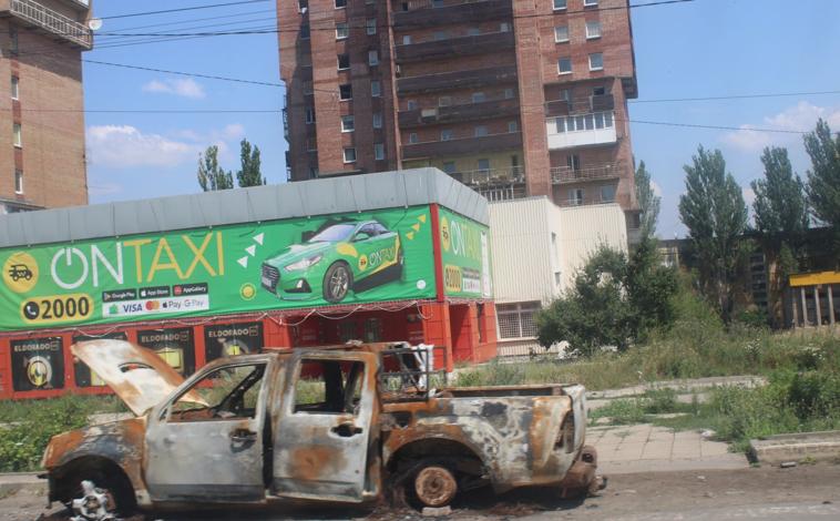 Imagen principal - En la primera imagen, coches despanzurrados y edificios acribillados dan la bienvenida a Kostiantynivka, en la primera linea del frente con Rusia. Oleksander y Kisley vigilan la llegada del enemigo, en la segunda foto. En la tercera: la munición que usa el Ejercito ucraniano para derribar drones 