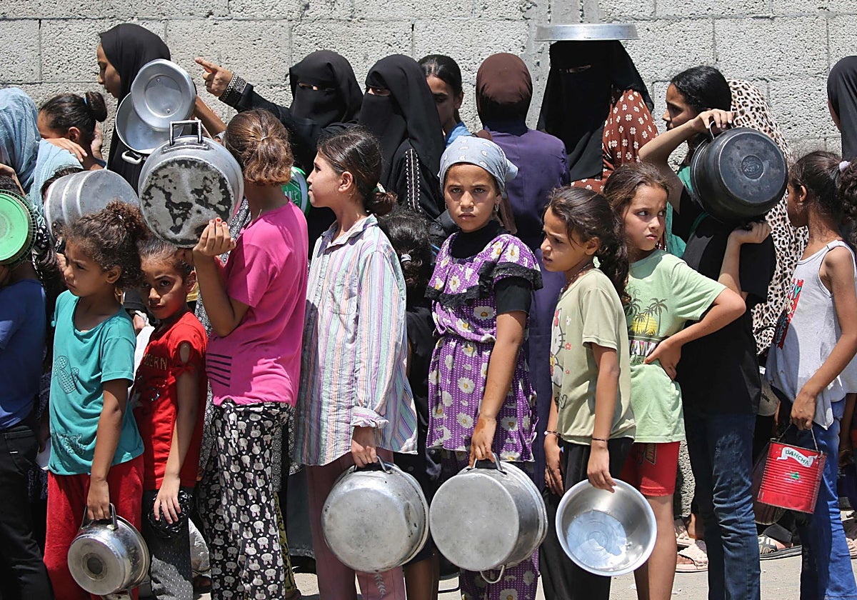 Niños gazatíes hacen cola para conseguir algo de comida en la Ciudad de Gaza