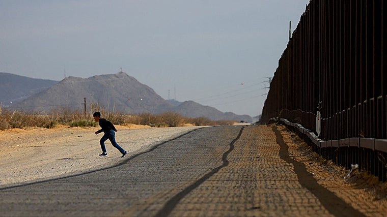 Un migrante corre después de ingresar a Estados Unidos sin ser detectado, a través de un agujero en una sección del muro fronterizo entre Estados Unidos y México, en Sunland Park, Nuevo México