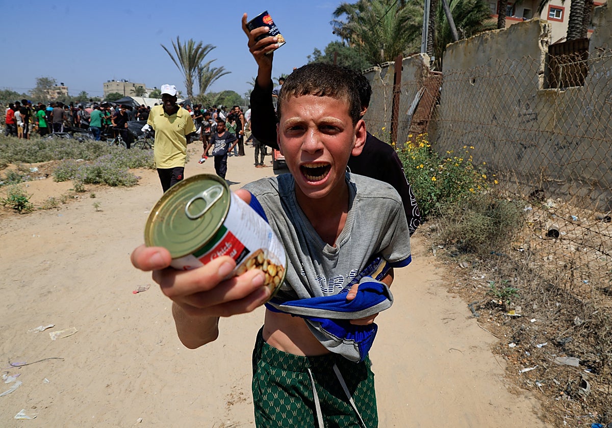 Foto: Un joven palestino sostiene una lata de garbanzos de un paquete de ayuda lanzado desde un avión cerca de Zawayda (Franja de Gaza) | Vídeoanálisis: El uso del hambre como herramienta de guerra