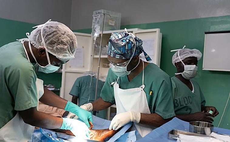 Imagen principal - MSF atienden en quirófano a un herido en el Hospital de Rutshuru, en la primera foto. En la segunda imagen, un joven herido, por un disparo de hombres armados mientras trabajaba en los campos de Kibirizi en agosto, se recupera en el hospital. En la tercera foto, el Dr. Karry Felix (MSF) repasa la lista de operaciones del día