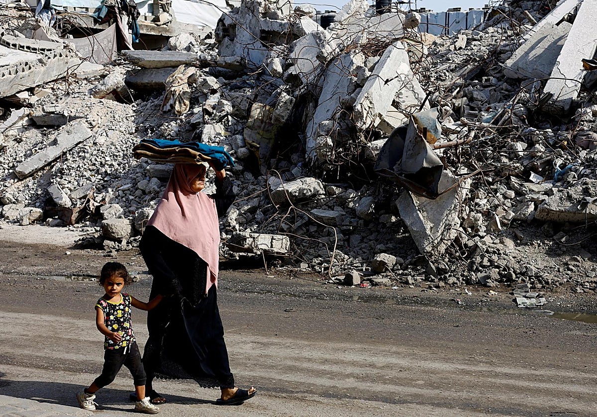 Palestinos caminan junto a un edificio residencial destruido en anteriores ataques israelíes, después de que Hamás aceptara liberar a los rehenes