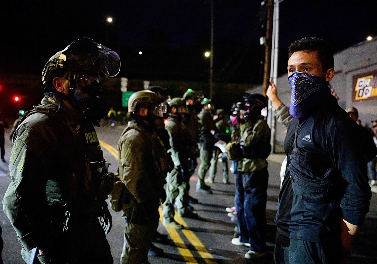 Agentes federales montan guardia para mantener a los manifestantes alejados de una instalación del Servicio de Inmigración y Control de Aduanas en el centro de Portland, Oregón