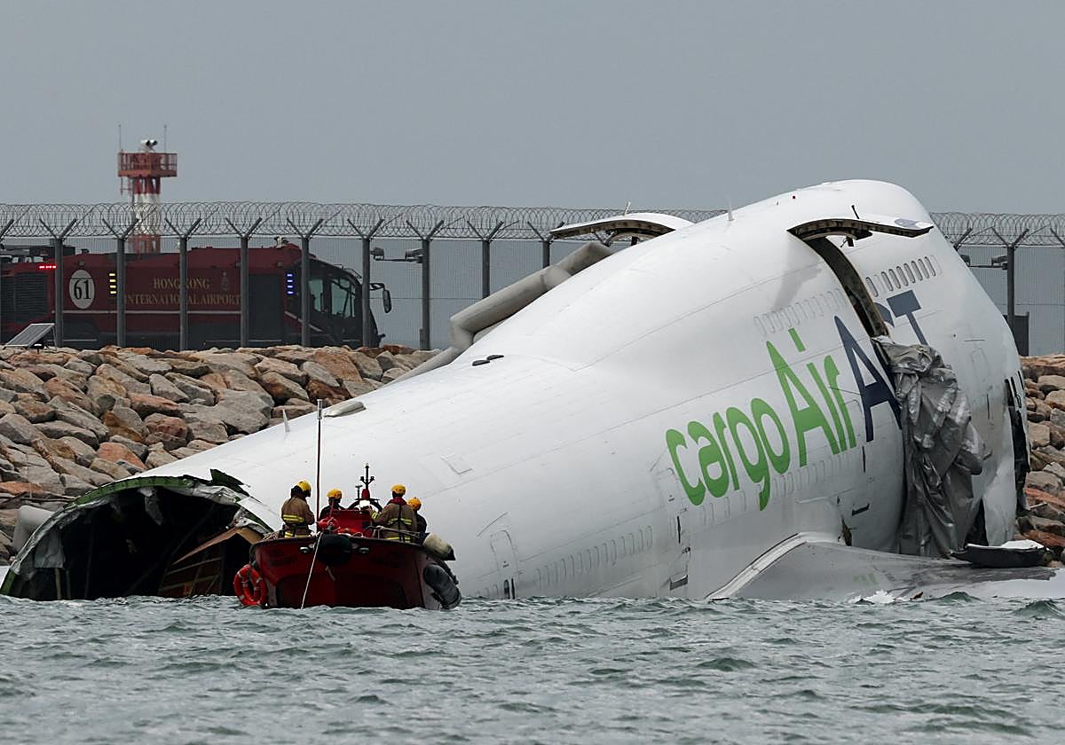 Personal de emergencia trabaja cerca de un avión de carga que se encuentra parcialmente en el mar después de desviarse de la pista durante el aterrizaje en el Aeropuerto Internacional de Hong Kong