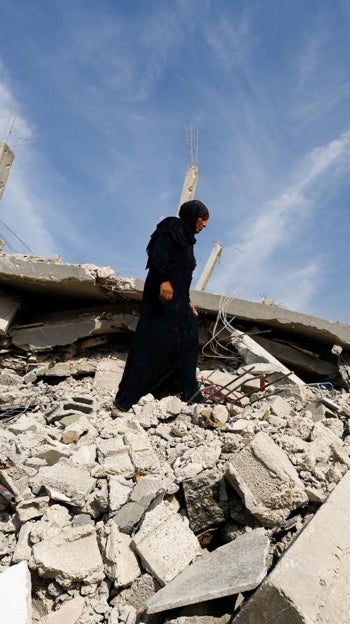 Una mujer camina sobre los escombros de un edificio destruido en Ciudad de Gaza