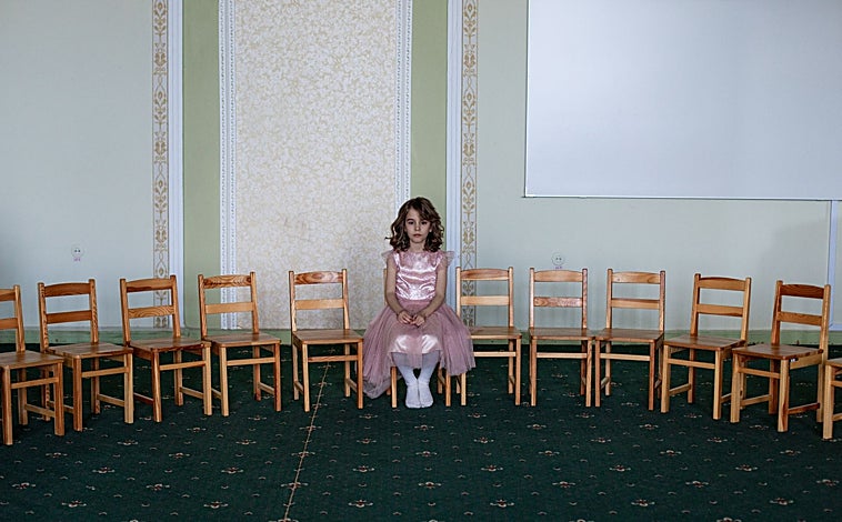 Imagen principal - El invierno demográfico que vive Ucrania se traduce una infancia solitaria, como la de Myroslava, de siete años, quien se quedó sin baile de fin de curso por la guerra (primera imagen), o entre escombros, como la de Misha, de nueve años, en su casa de Chernihiv (segunda imagen). En Ucrania, los niños juegan en los parques bajo las ruinas de los edificios bombardeados (tercera imagen) 