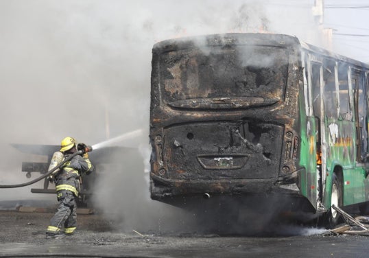 Bomberos de Guadalajara intentan apagar un vehículo incendiado tras la muerte del Mencho