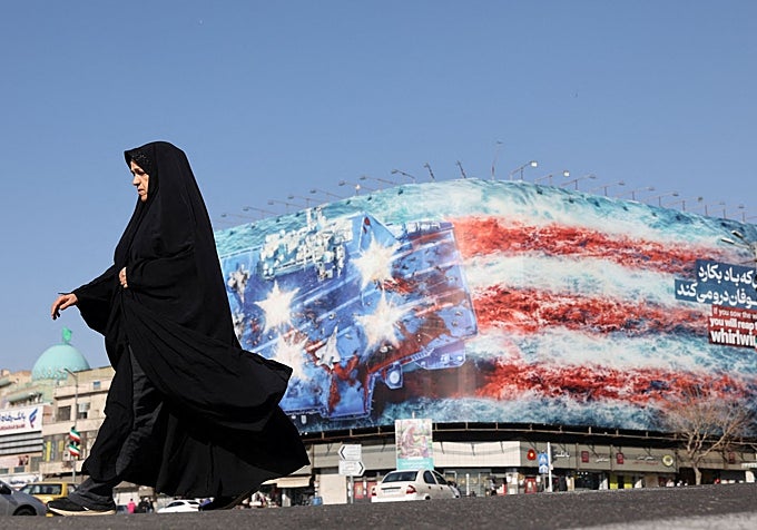 Una mujer iraní pasa junto a una valla publicitaria antiestadounidense en Teherán.
