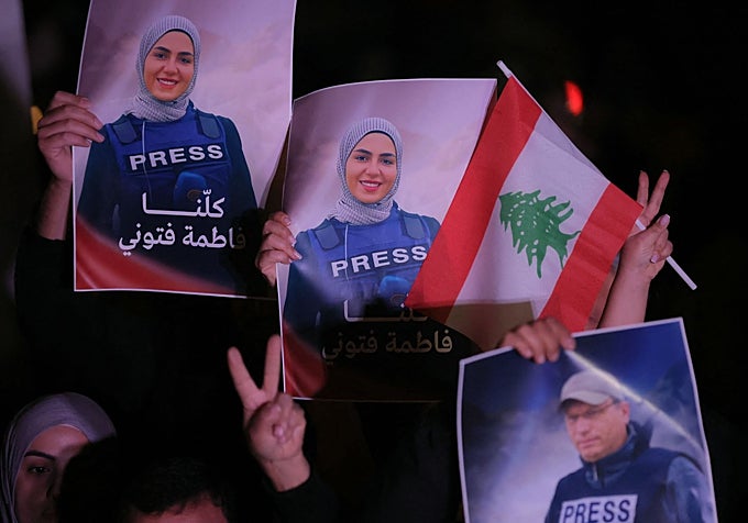 Varias personas portan fotografías de los periodistas Fatima Ftouni y Ali Shoeib en el centro de Beirut, en protesta por su muerte a causa de un ataque israelí.