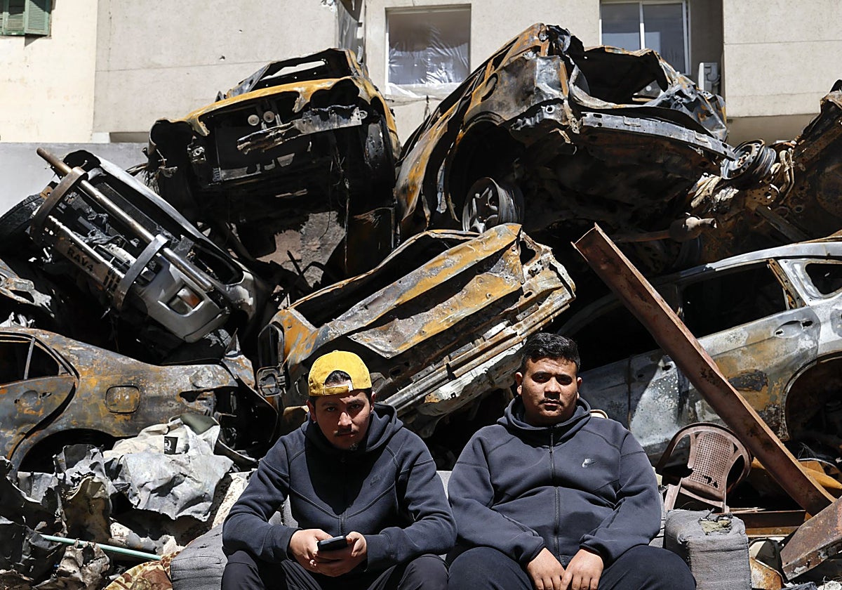 Dos jóvenes, ante una montaña de coches destrozados en una de las zonas más golpeadas por los ataques de Israel sobre Beirut.