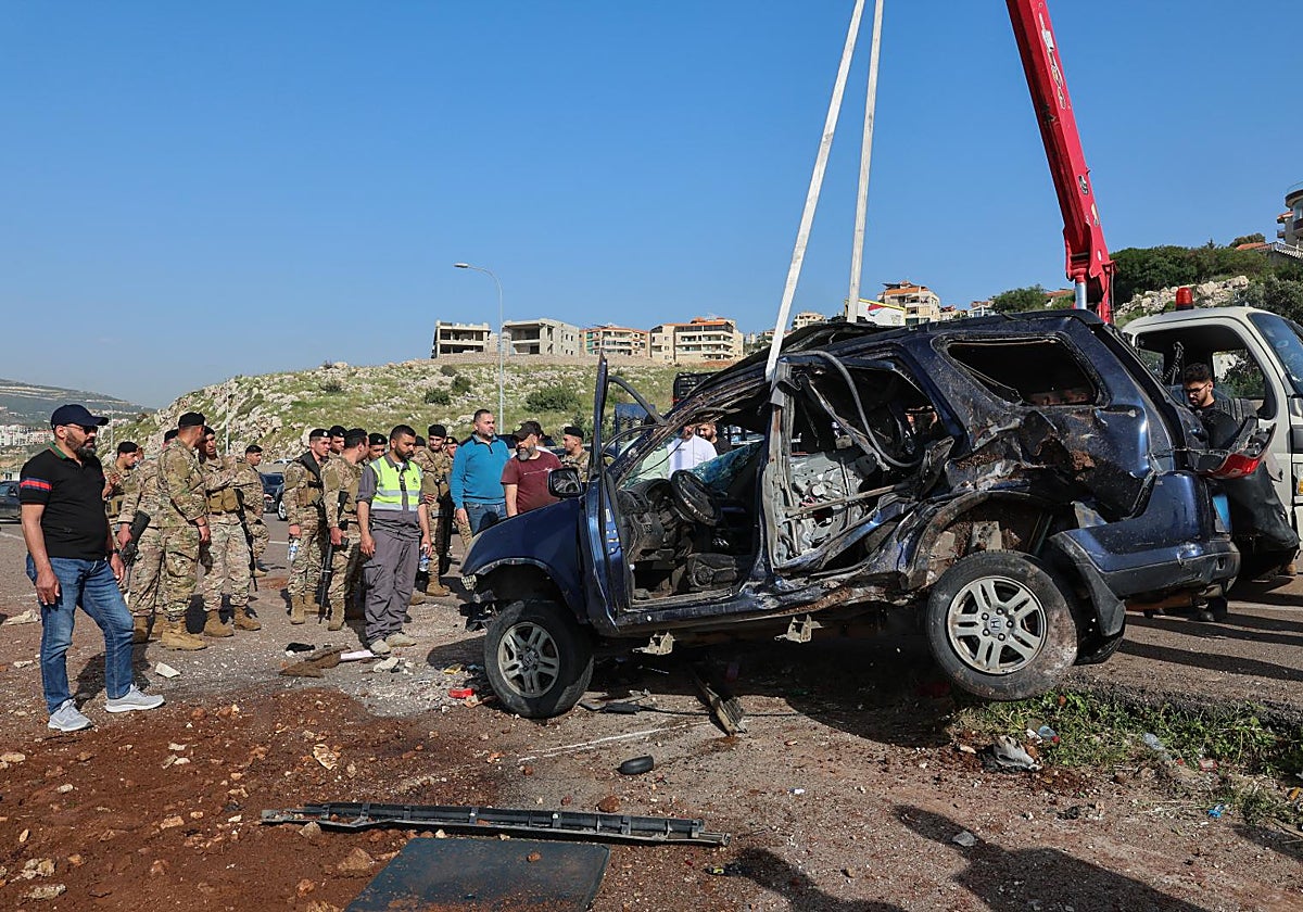 Unos trabajadores retiran los restos de un vehículo destrozado por un ataque israelí al sur de Beirut.