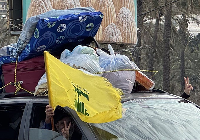 Con su coche cargado hasta los topes, una familia regresa a su casa del sur del Líbano ondeando la bandera de Hizbolá.