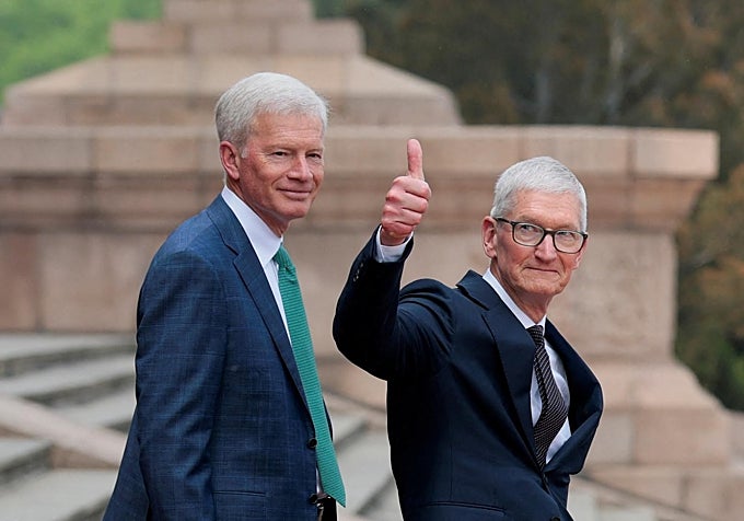 Tim Cook alza el pulgar junto al consejero delegado de Cargill, Brian Sikes, en las escalinatas del Gran Palacio del Pueblo.