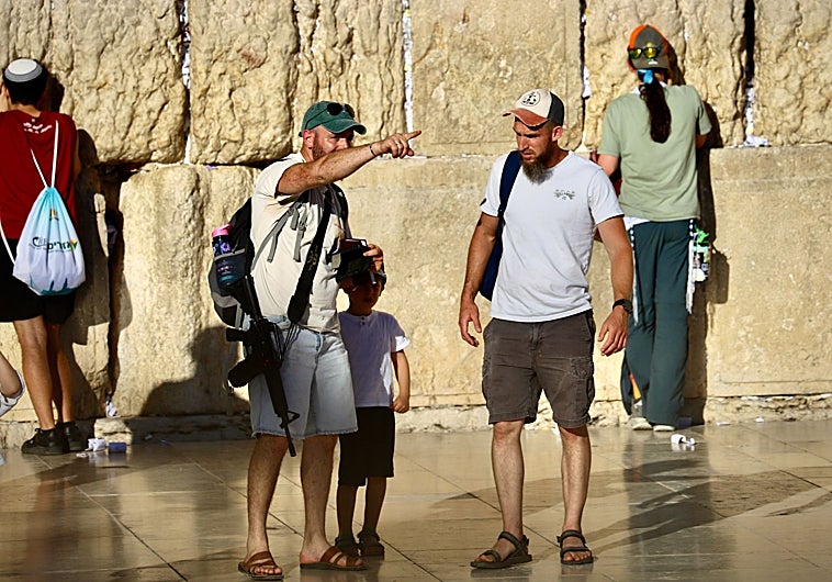 Imagen principal - En el Muro de las Lamentaciones de Jerusalén, fieles con fusiles de asalto al hombro (primera foto) rezan junto a judíos ultraortodoxos (segunda foto y tercera foto), bajo fuertes medidas de seguridad para impedir atentados islamistas.  