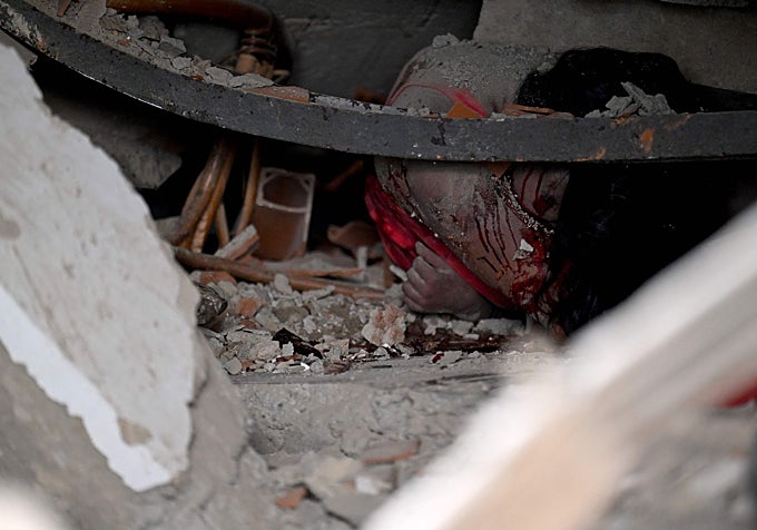Un cuerpo yace atrapado bajo los escombros de un edificio derrumbado en La Guaira