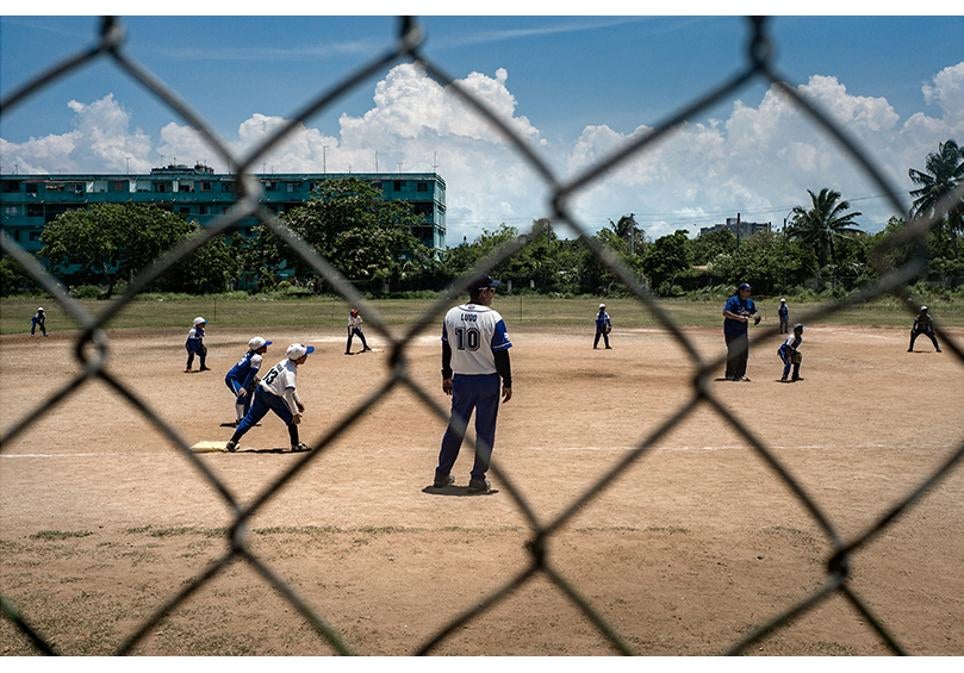 Un grupo de jóvenes juega al béisbol en su barrio.