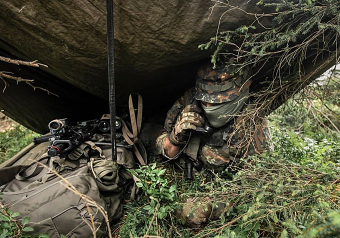 Con equipo de camuflaje, un militar de guerra electrónica vigila las comunicaciones en un refugio.