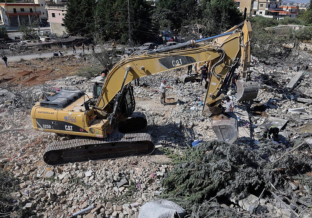 Una excavadora trabaja mientras los equipos de rescate buscan supervivientes tras un ataque aéreo israelí contra un edificio en la localidad de Kfar Rumman.