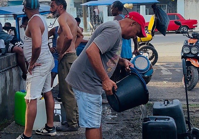 Un hombre llena varios bidones con agua