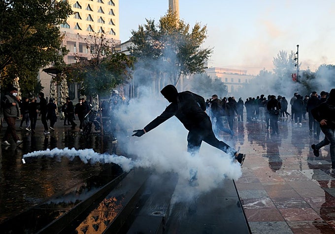 Un manifestante lanza una granada de gas lacrimógeno durante los enfrentamientos en una manifestación antigubernamental de estudiantes en Tirana, Albania, este domingo