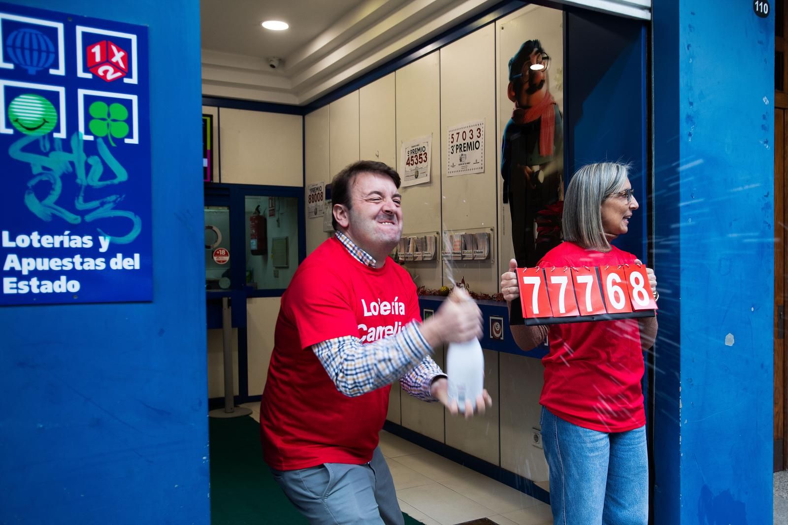 Un hombre celebra abirendo con una botella el tercer premio en una administración de Vigo