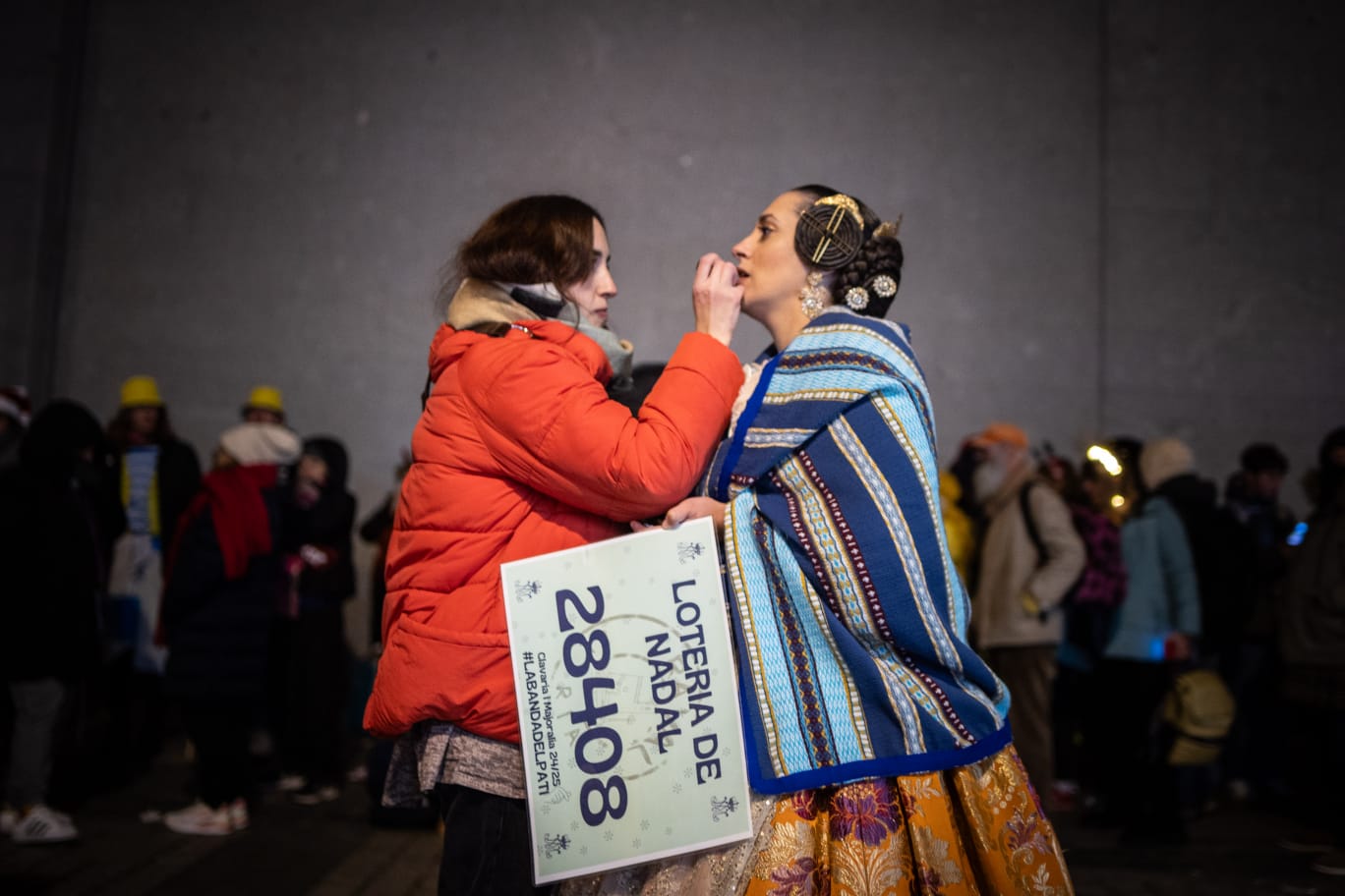 Ataviada con la vestimenta de fallera, una mujer es maquillada antes de entrar al sorteo de la Lotería de Navidad.