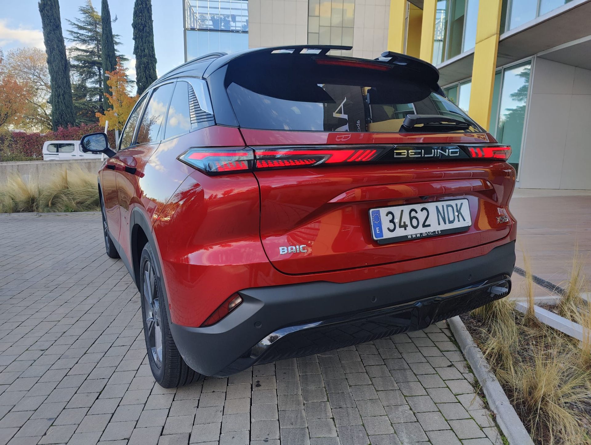 Bajo la fina rejilla que los une, encontramos un gran escudo frontal con formas romboidales parametrizadas y en contraste, un leitmotiv que encaja perfectamente con el utilizado en el diseño de los faros. Una repetición de motivos que nos volvemos a encontrar en la parte posterior del nuevo BAIC X55. Ahí, su gran pieza central une ambos grupos ópticos y, entre ambos, luce el nombre de la ciudad donde nació la marca: Beijing.