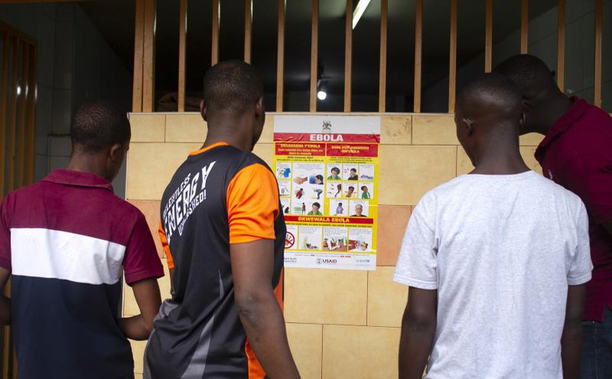 Unos jóvenes leen un cartel con medidas de prevención en Kampala