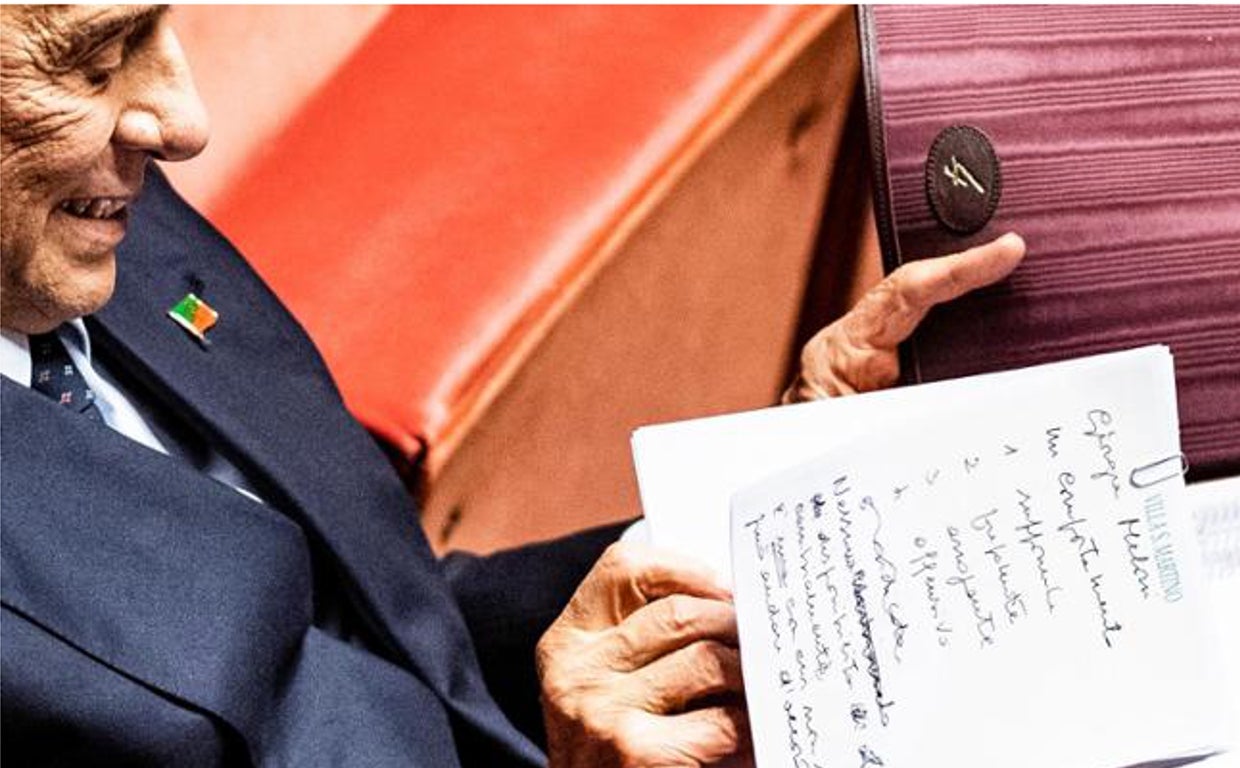 Berlusconi con su blog de notas donde tenía escrito las referencias a Meloni