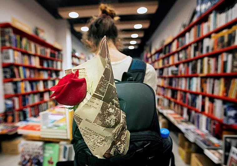 Una mujer con una rosa en la mochila en una librería del centro de Barcelona