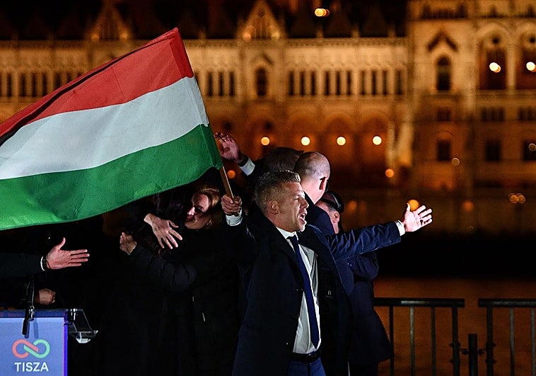 Peter Magyar, líder del partido conservador proeuropeo TISZA, ondea la bandera de Hungría en la ribera del Danubio frente al Parlamento durante la celebración de su amplia victoria electoral en las elecciones parlamentarias del 12 de abril de 2026.