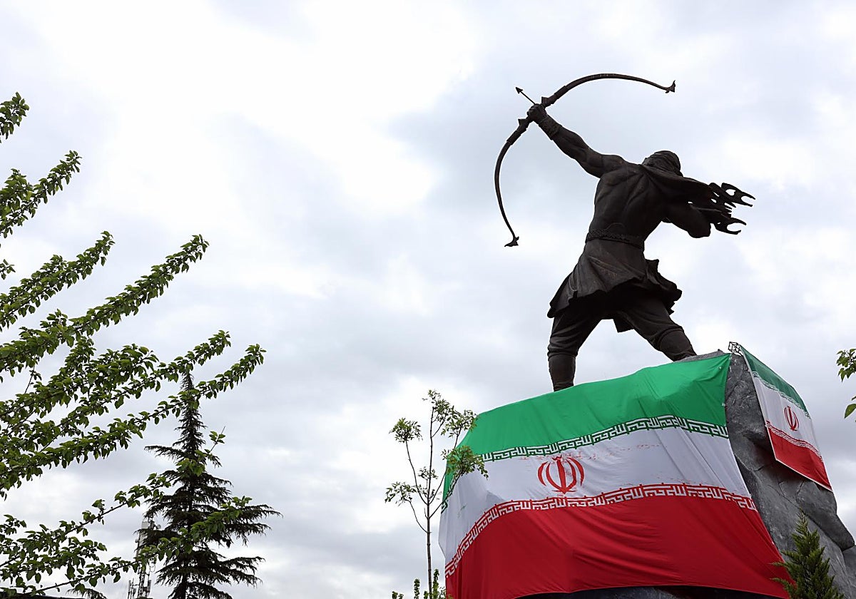 Banderas nacionales iraníes envuelven una estatua en una plaza de Teherán