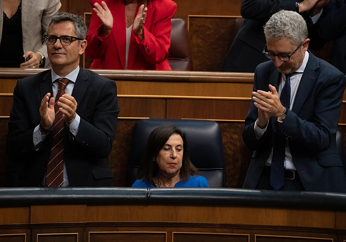 Félix Bolaños y Arcadi España aplauden mientras Margarita Robles, permanece sentada durante una sesión en el Congreso