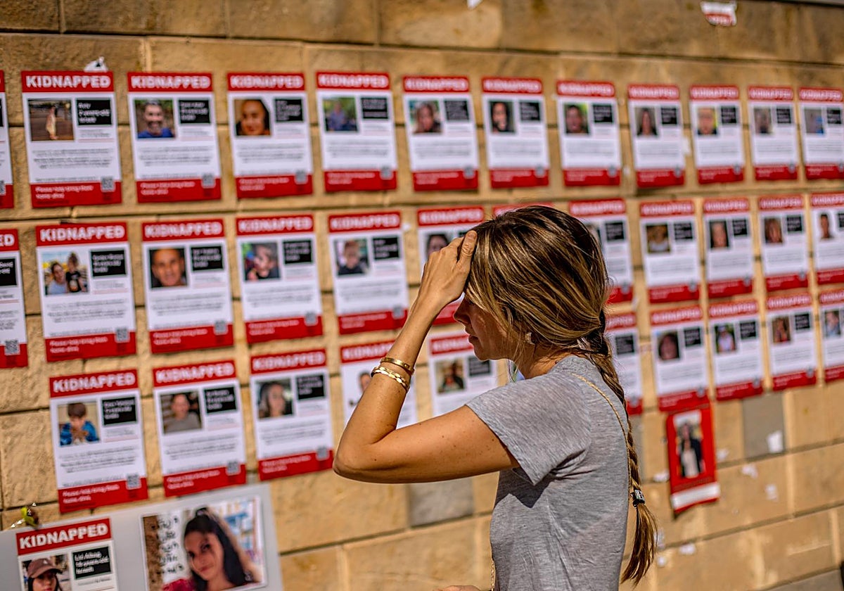 Una joven contempla los carteles que anunciaban los cientos de secuestros de Hamás en el 7-O, en Tel Aviv