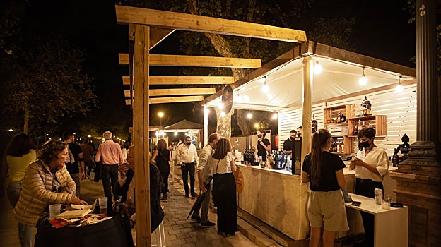 Varias personas bebiendo y comiendo en uno de los puestos gastronómicos del Icónica Sevilla Fest 2022